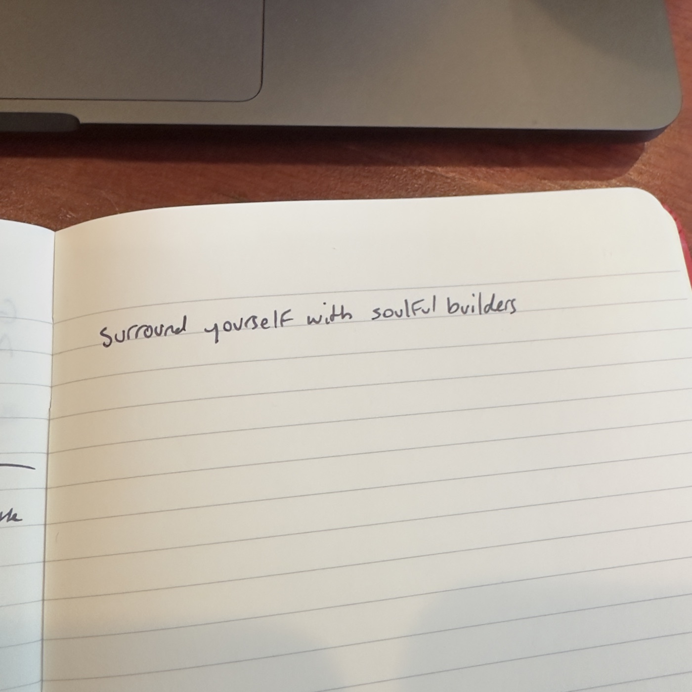 Handwritten in a notebook beside a laptop: Surround yourself with soulful builders