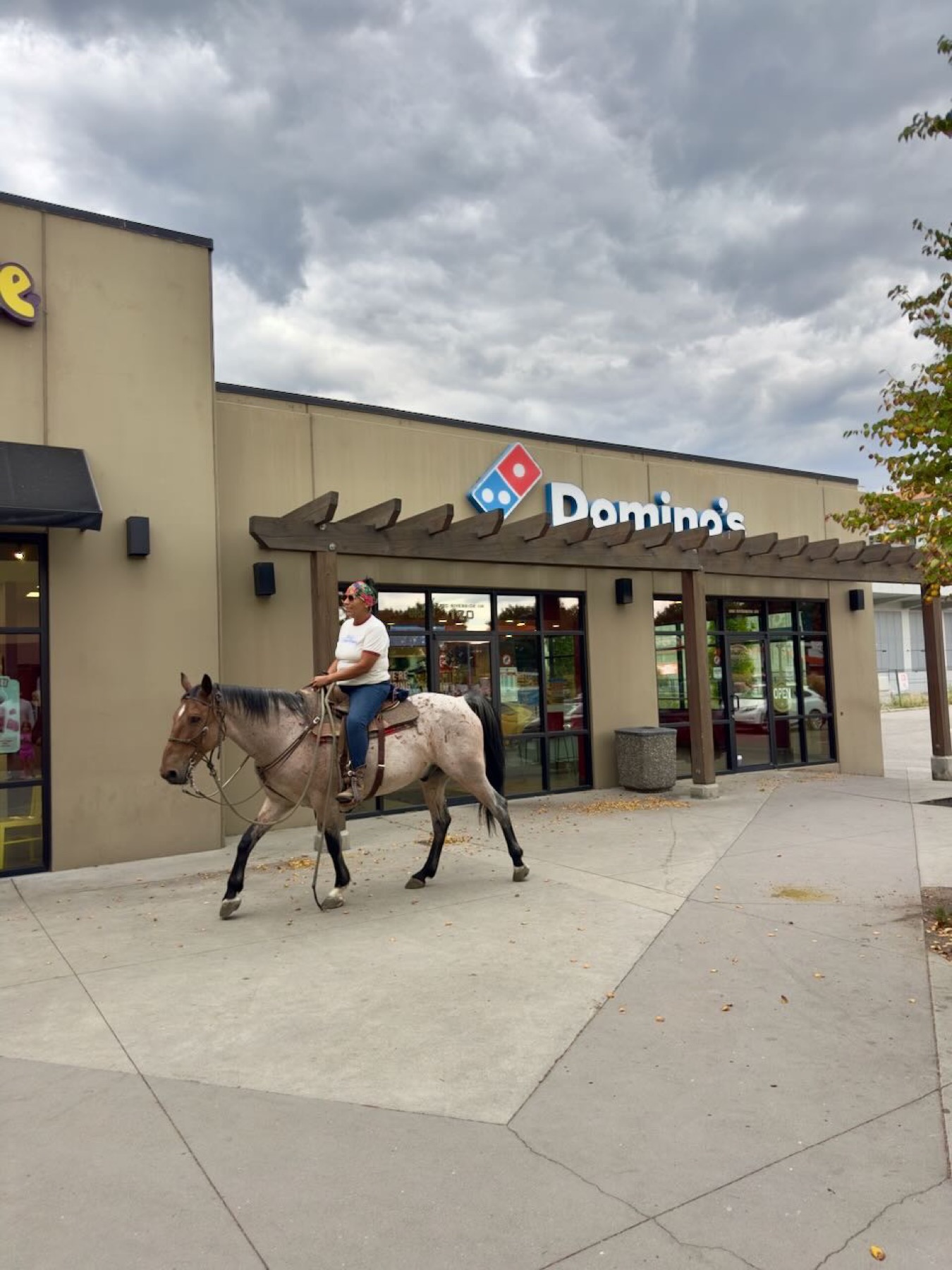 A woman riding a horse past a Domino's