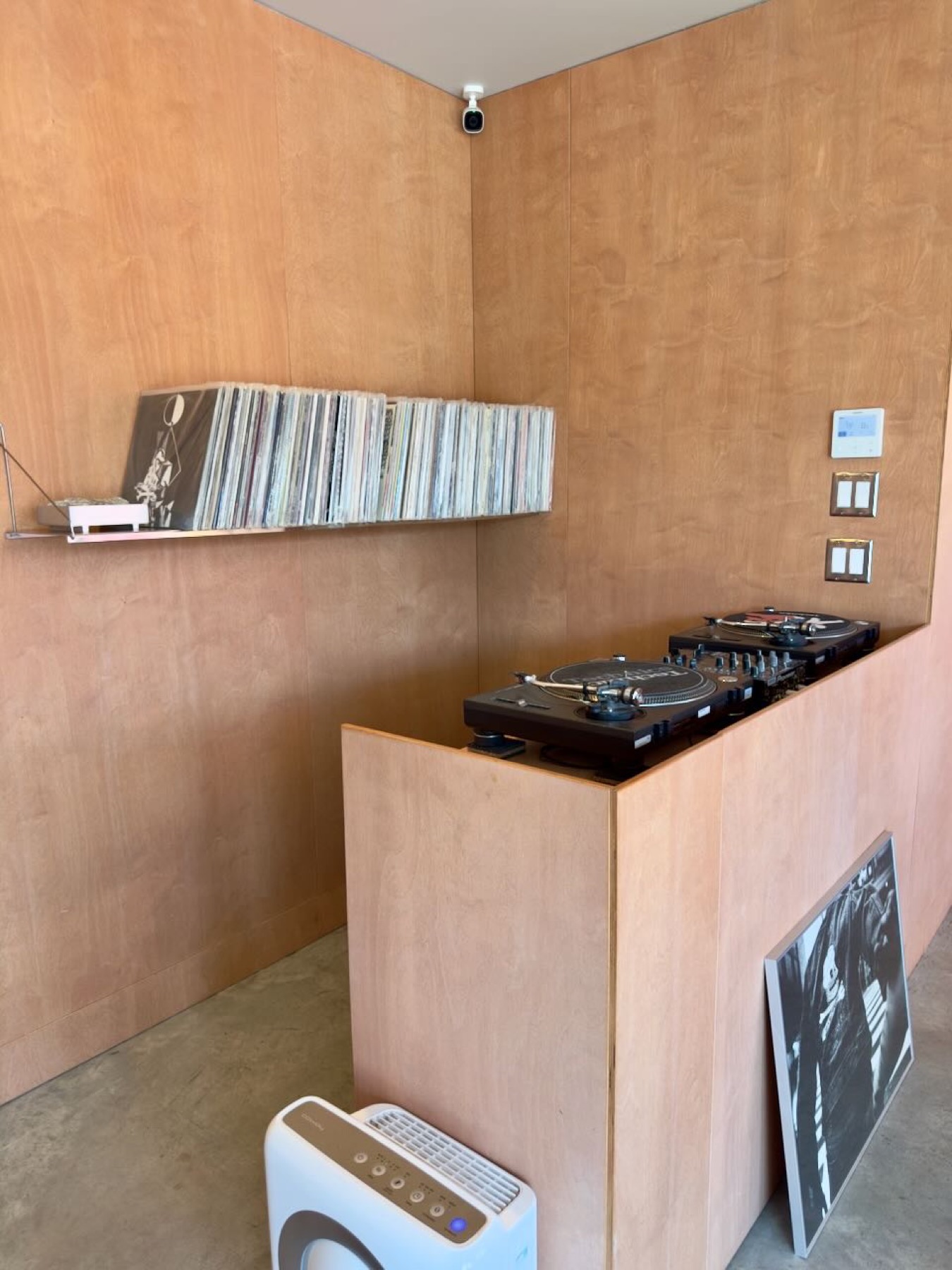 Turntables and a shelf of records in a plywood-lined room