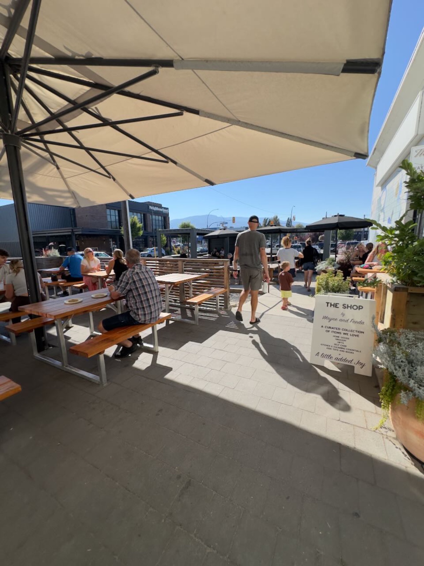 The patio outside Wayne & Freda, picnic tables under umbrellas and a sign for The Shop