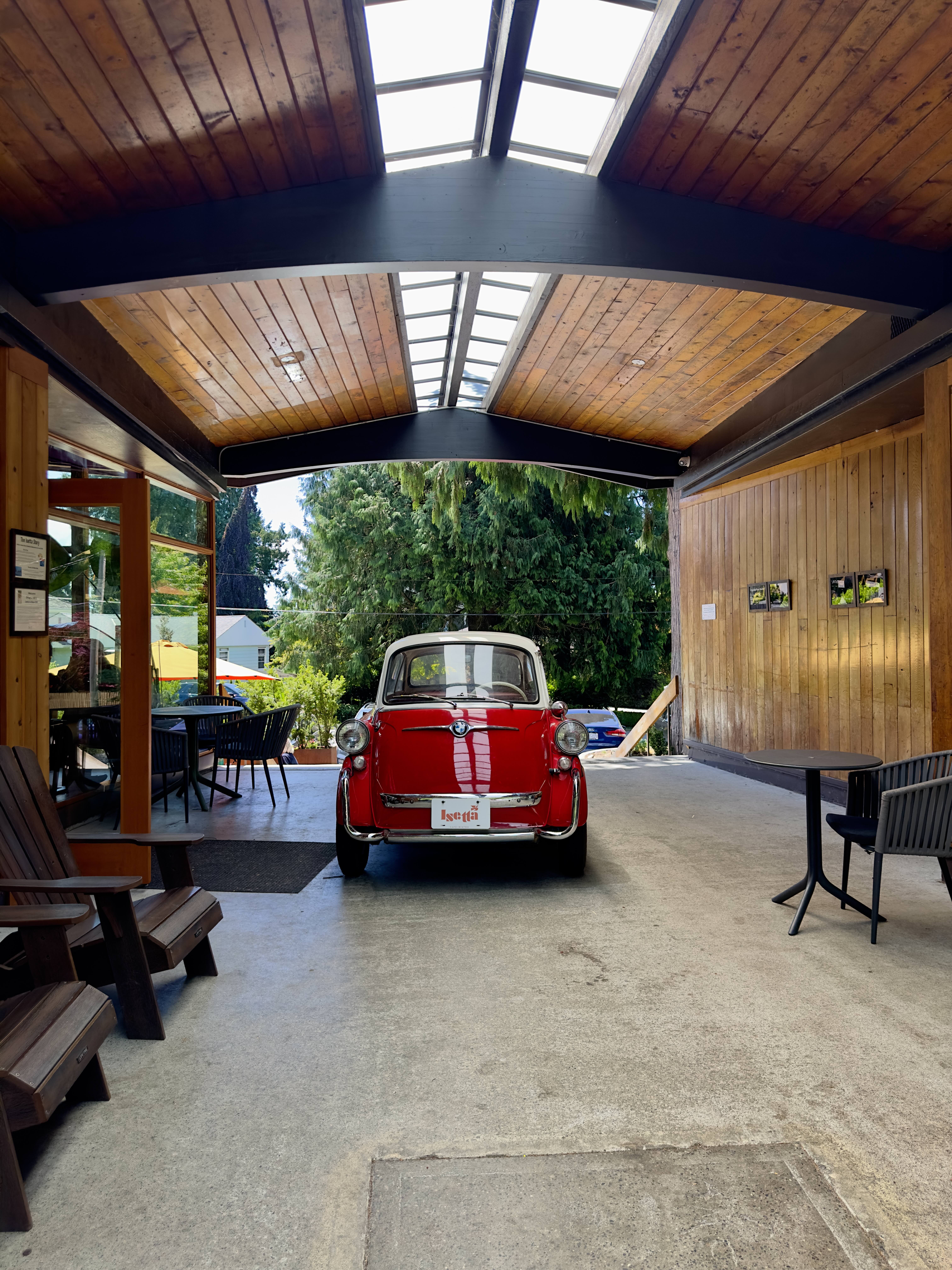 Vintage red BMW Isetta parked under a wood-beamed carport